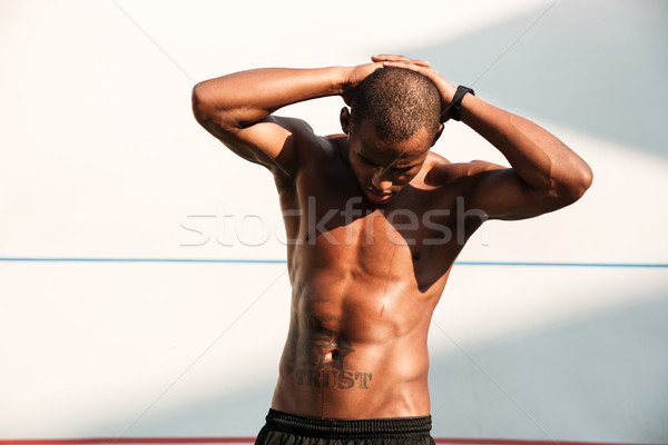 Portrait of a handsome african sports man with hands behind the  Stock photo © deandrobot