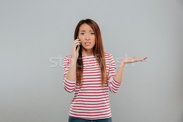 Zavart fiatal ázsiai nő beszél telefon Stock fotó © deandrobot