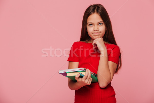 Thuoghtdul girl in red dress holding book and looking camera isolated Stock photo © deandrobot