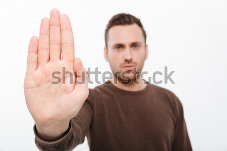 Handsome young serious man showing stop gesture. Stock photo © deandrobot