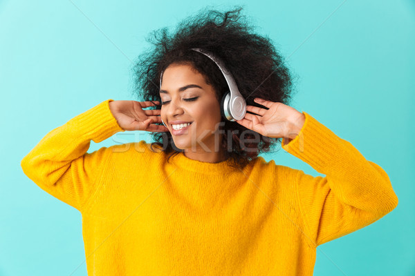 African american glad woman in yellow shirt listening to music v Stock photo © deandrobot