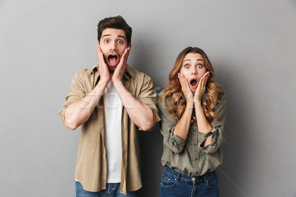 Portrait of a shocked young couple standing together Stock photo © deandrobot