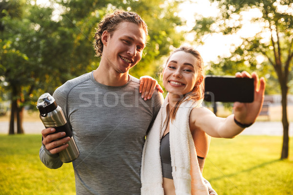 Fitness sport loving couple holding bottle with water. Stock photo © deandrobot