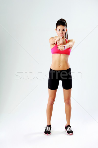 Young happy sport woman stretching hands on gray background Stock photo © deandrobot