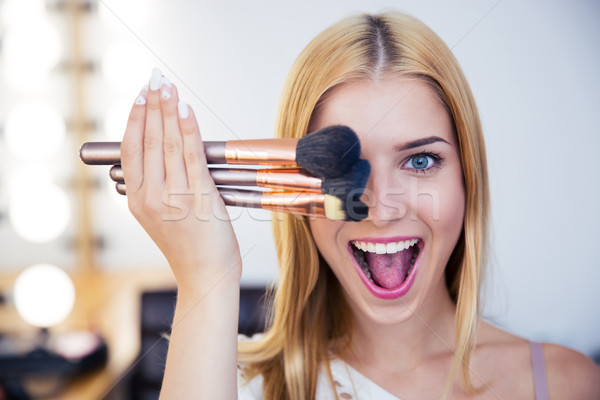 Woman covering her eye with brushes  Stock photo © deandrobot