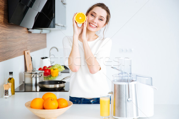 Happy woman with orange half making fresh juice  Stock photo © deandrobot