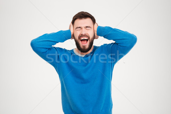Young man covering his ears and screaming  Stock photo © deandrobot