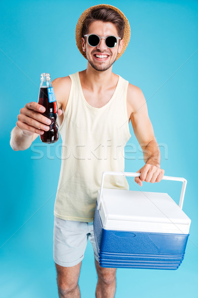 Cheerful man giving you cooling bag and bottle of soda Stock photo © deandrobot
