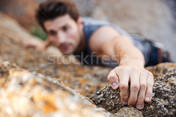 Man reaching for a grip while he rock climbs Stock photo © deandrobot