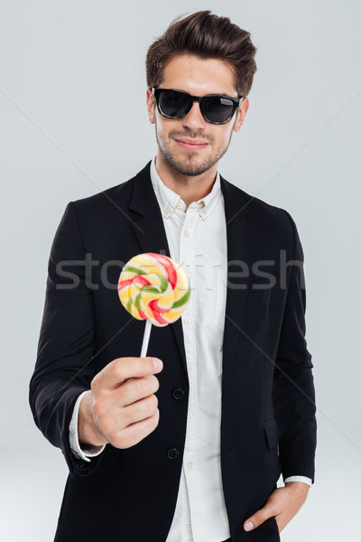 Businessman in sunglasses standing with hand in pocket holding lollipop Stock photo © deandrobot