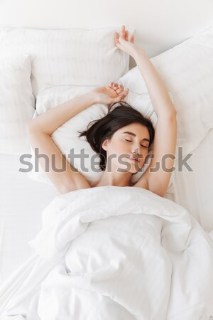 Happy young woman lying in bed and showing ok gesture Stock photo © deandrobot