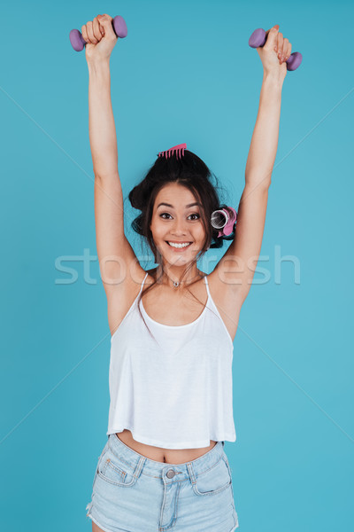 Happy young lady with hair curlers holding dumbbells Stock photo © deandrobot