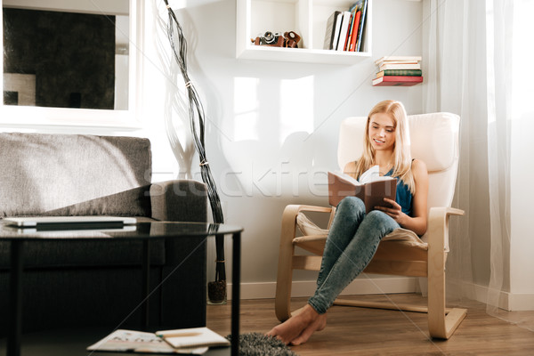 Woman sitting and reading book at home Stock photo © deandrobot