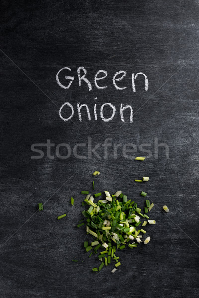 Cut green onion over dark chalkboard background. Stock photo © deandrobot