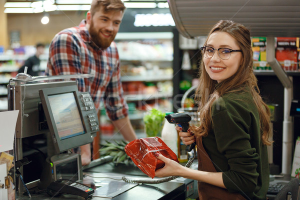 Happy cashier woman on workspace in supermarket Stock photo © deandrobot