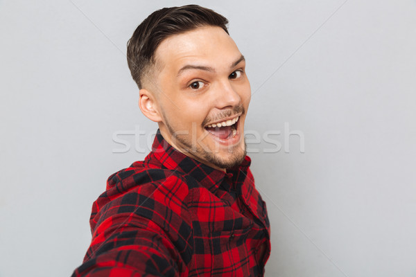 Happy man standing sideways and looking at camera Stock photo © deandrobot