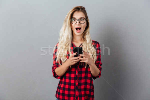 Happy shocked young blonde woman chatting by phone. Stock photo © deandrobot