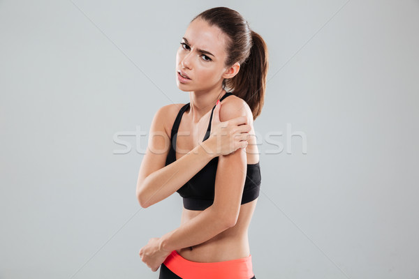 Vista laterale sconvolto fitness donna dolore spalla grigio Foto d'archivio © deandrobot