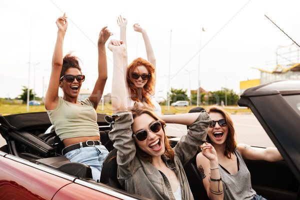 Happy emotional four young women friends sitting in car Stock photo © deandrobot