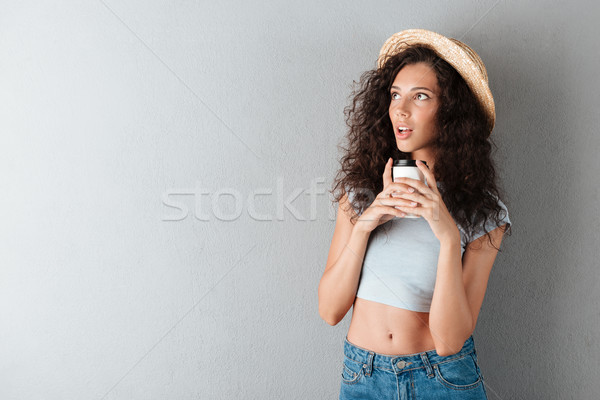 Meglepődött fürtös nő kalap iszik kávé Stock fotó © deandrobot