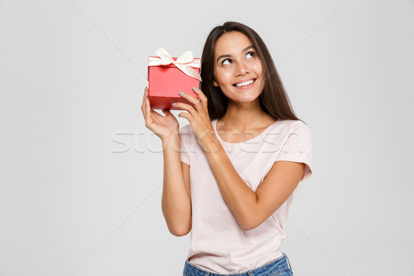 Portrait of a cheerful young asian woman holding present box Stock photo © deandrobot