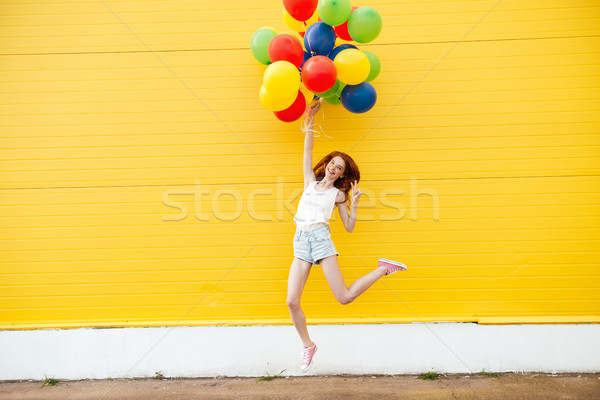 Sorridere donna jumping giallo muro Foto d'archivio © deandrobot