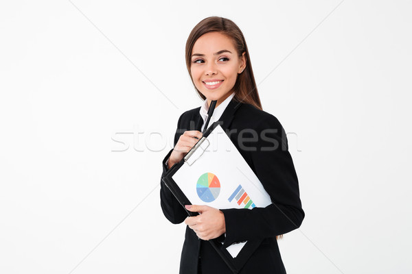Happy business woman holding clipboard. Looking aside. Stock photo © deandrobot