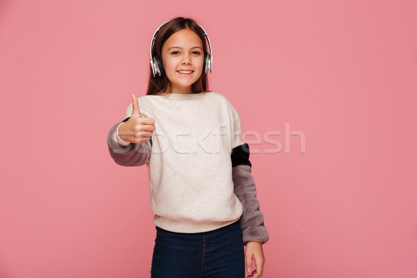 Cheerful positive girl in headphones showing thumb up isolated Stock photo © deandrobot