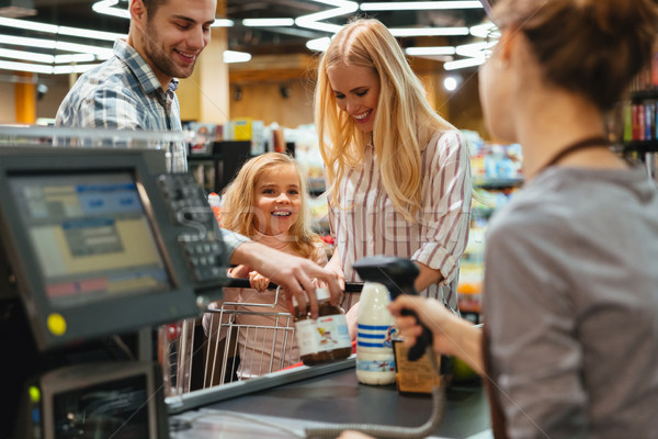 Happy family standing at the cash counter Stock photo © deandrobot