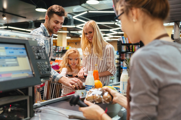 Young family standing at the cash counter Stock photo © deandrobot