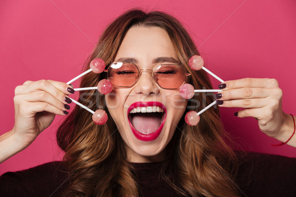 Excited screaming woman wearing glasses holding a lot of sweeties. Stock photo © deandrobot