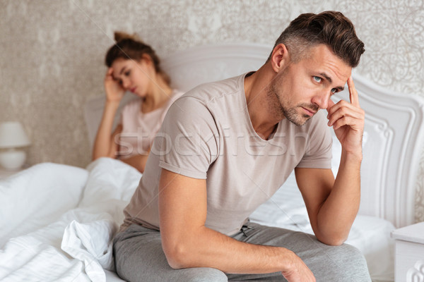 Upset pensive man sitting on bed with his girlfriend Stock photo © deandrobot