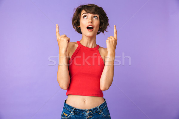 Portrait of a cheerful young girl pointing fingers up Stock photo © deandrobot
