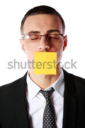 Portrait of businessman with mouth covered with a paper card over white background Stock photo © deandrobot