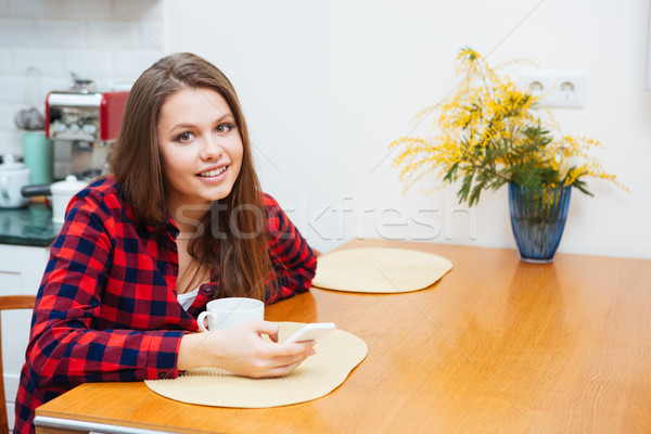 Smiling lovely young woman drinking coffee at home Stock photo © deandrobot