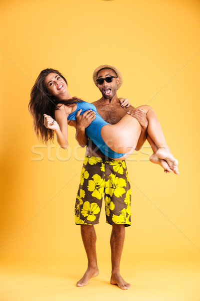 Afro american man holding his girlfriend with two hands Stock photo © deandrobot