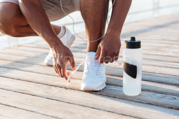 Cropped image of african american young sportsman laces his sneakers Stock photo © deandrobot