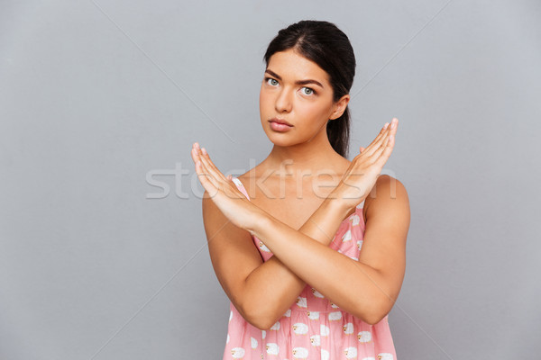 Stock photo: Serious young woman with hands crossed showing stop gesture