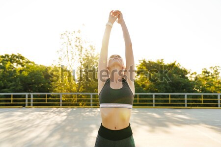 Portrait of a sports woman stretching leg outdoors Stock photo © deandrobot