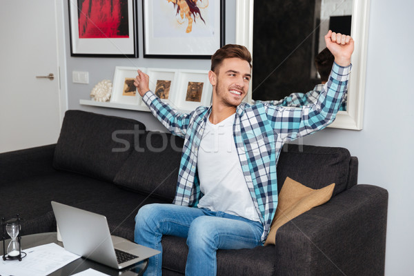 Cheerful bristle man using laptop computer while stretching. Stock photo © deandrobot