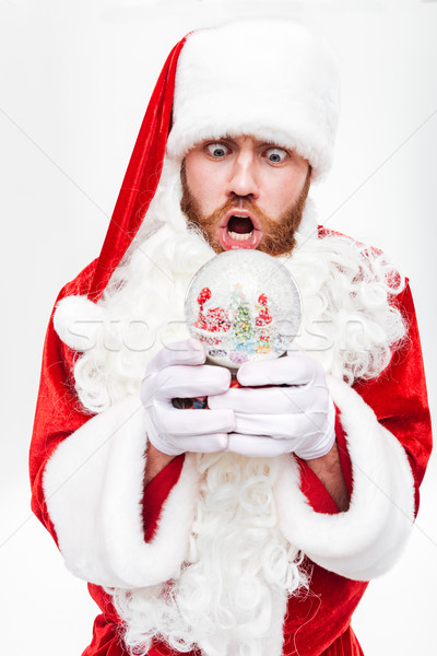 Shocked astonished man santa claus standing and holding snow ball Stock photo © deandrobot