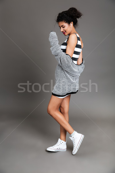 Stock photo: Young african american woman listening to music with earphones