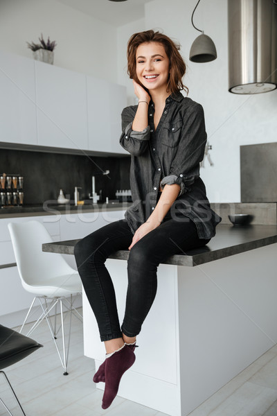 Cheerful lady sitting at kitchen indoors. Stock photo © deandrobot