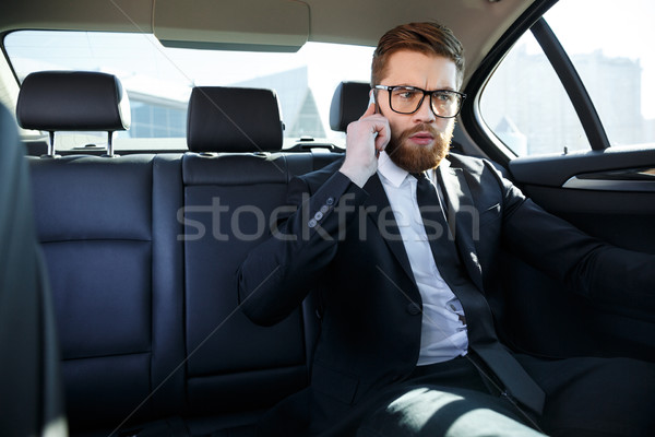 Stock photo: Frustrated business man in eyeglasses talking on mobile phone