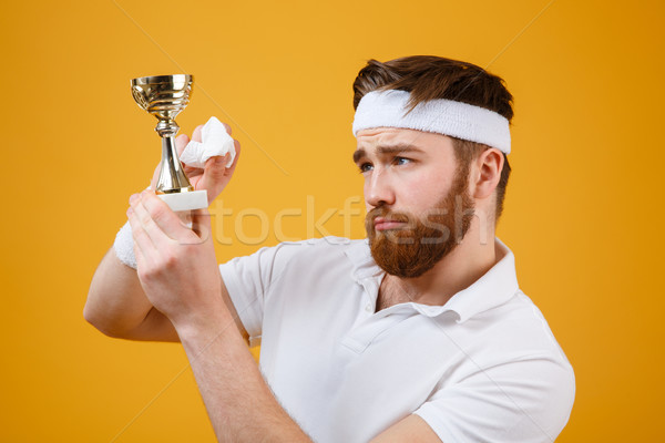 Handsome young sportsman holding reward and wipe with a napkin Stock photo © deandrobot