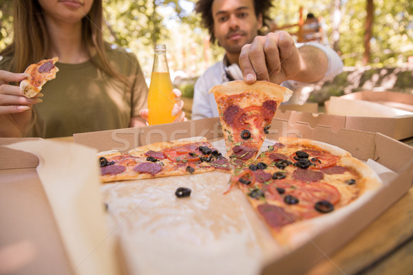 Cropped image of multiethnic friends students drinking juice eating pizza. Stock photo © deandrobot