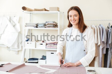 Pretty woman looking camera while holding pile of fabrics Stock photo © deandrobot