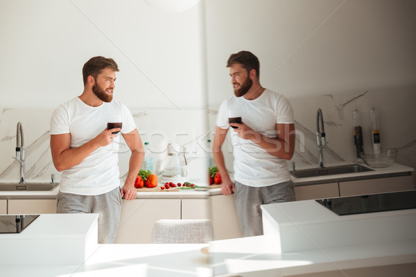 Side view of bearded man on kitchen with ice drink Stock photo © deandrobot