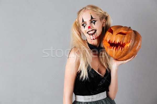 Smiling blonde woman in halloween make-up posing with carved pumpkin Stock photo © deandrobot