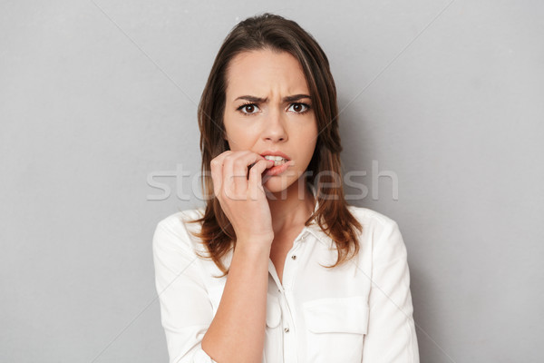 Portrait of a worried young business woman biting nails Stock photo © deandrobot